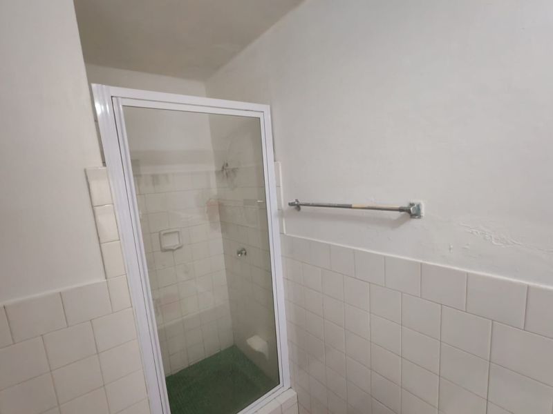 A functional bathroom featuring a shower enclosure with tiled walls and a wall-mounted towel rail, requiring minor cosmetic updates.