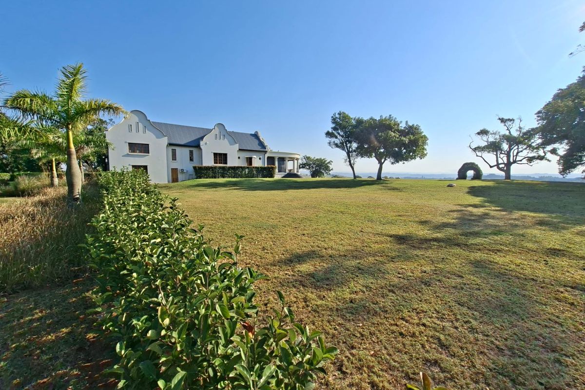 A spacious rear garden featuring a well-maintained lawn and a white gabled residential building with a covered patio area.