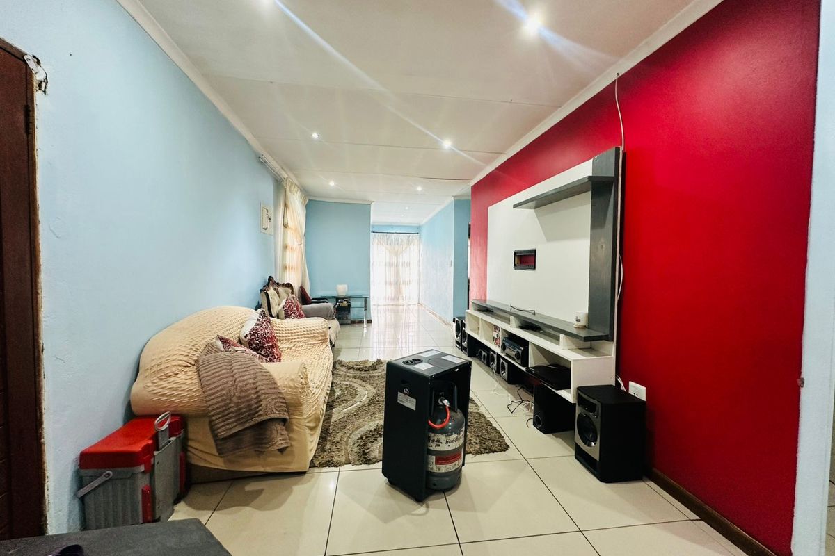 Living room featuring tiled flooring, recessed downlights, and a built-in media unit against a bold red accent wall.