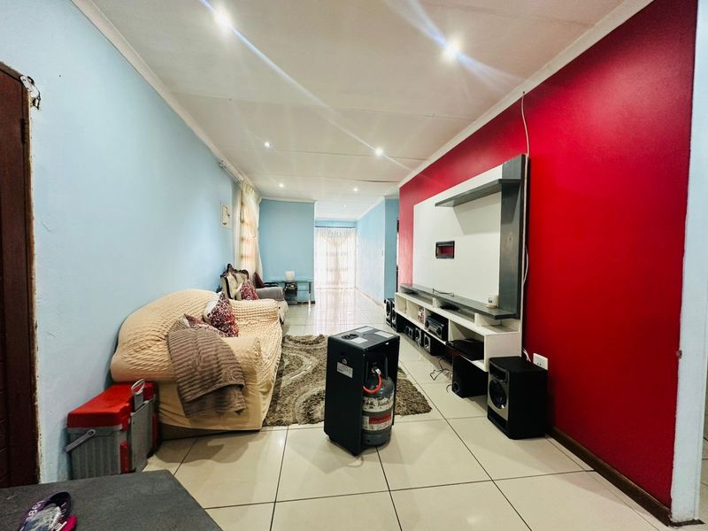 Living room featuring tiled flooring, recessed downlights, and a built-in media unit against a bold red accent wall.