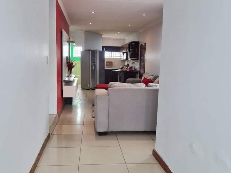 An open-plan living and kitchen area featuring tiled flooring and recessed lighting, providing a functional layout for modern living.