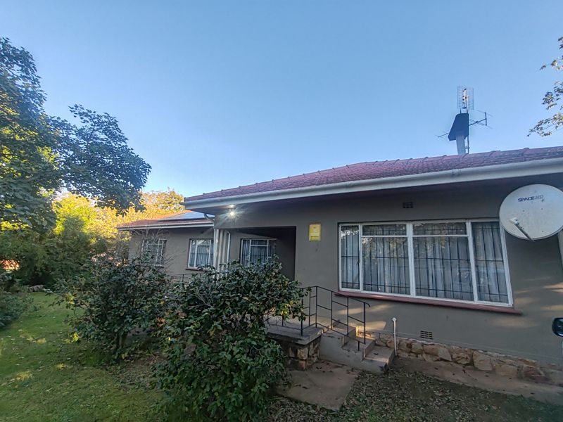 Front elevation of a single-story house featuring a tiled roof, stone base detailing, security bars on windows, and a covered entrance porch.