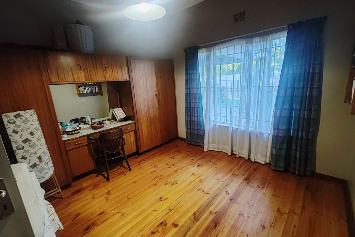 A bedroom featuring polished timber flooring and extensive built-in wooden cabinetry with an integrated vanity unit.