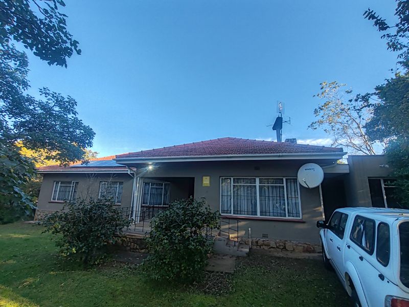 Front elevation of a single-story house featuring a tiled roof, solar panels, and security bars on windows, set within a garden area.