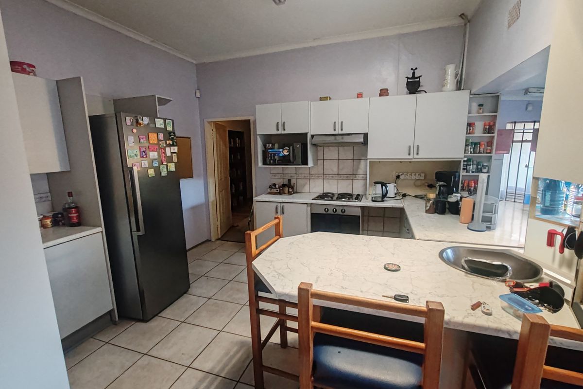 A functional kitchen featuring built-in cabinetry, a hob, oven, extractor fan, and tiled flooring with a breakfast nook area.