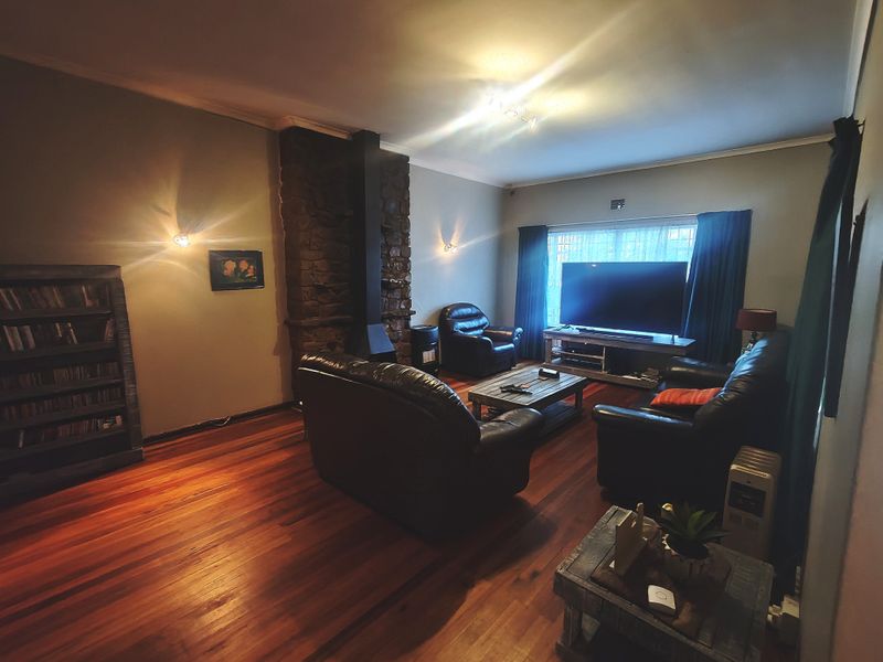 Spacious living room featuring warm hardwood flooring and a prominent stone fireplace with a built-in wood burning stove.