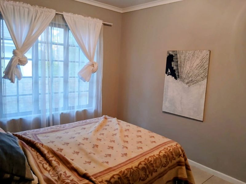A bedroom featuring neutral wall tones, tiled flooring, and a window with natural light.