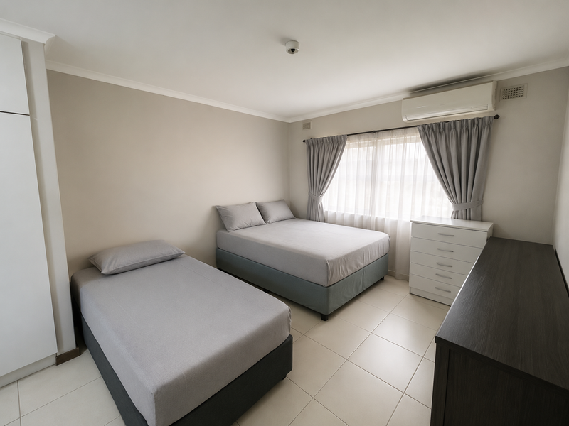 A well-maintained bedroom featuring tiled flooring, a built-in wardrobe, and a wall-mounted split-system air conditioner for climate control.