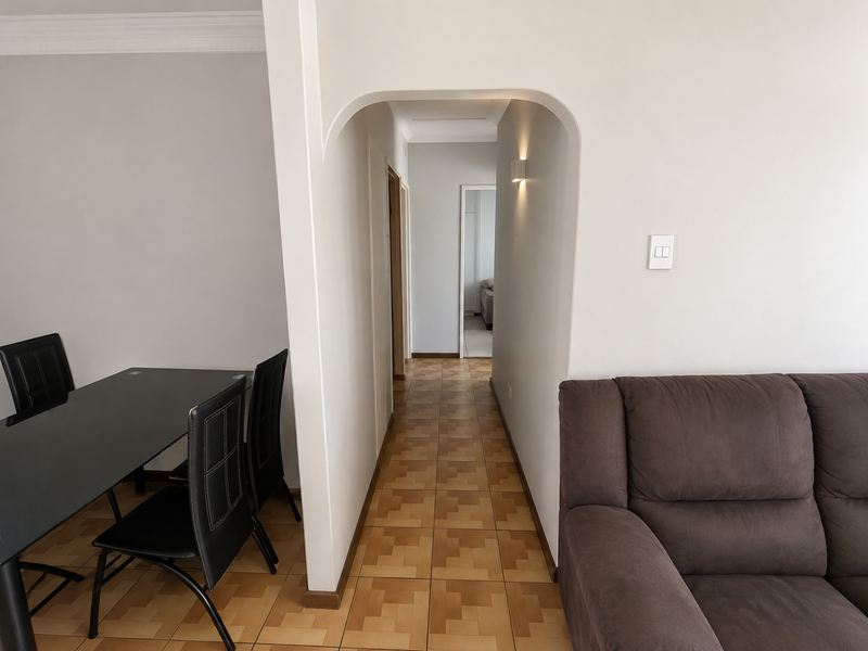 A view through an arched doorway into a hallway with tiled flooring, connecting the living and dining areas.