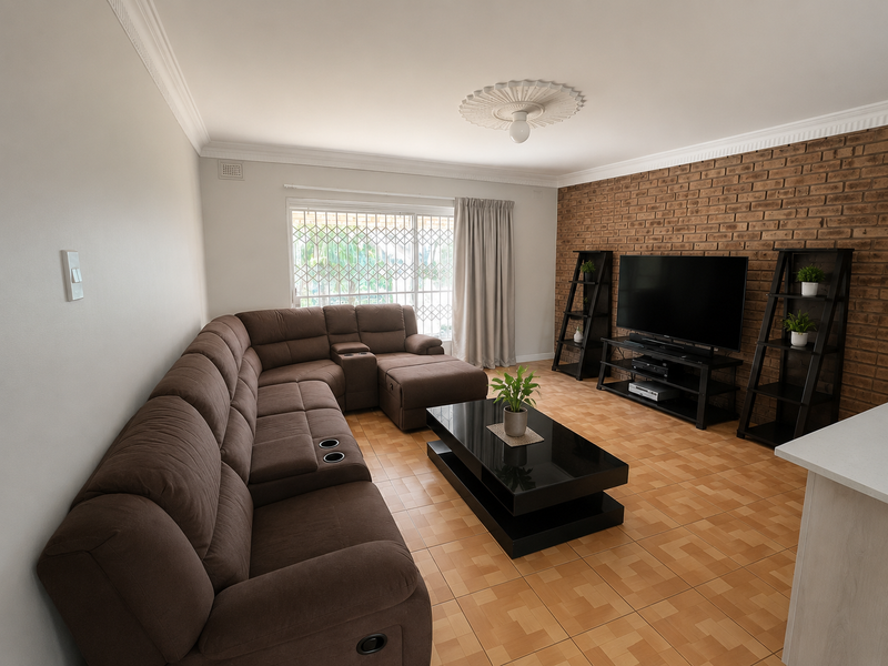 A comfortable living room featuring an exposed brick accent wall, ceramic floor tiles, and a decorative ceiling rose, providing a warm and inviting atmosphere.