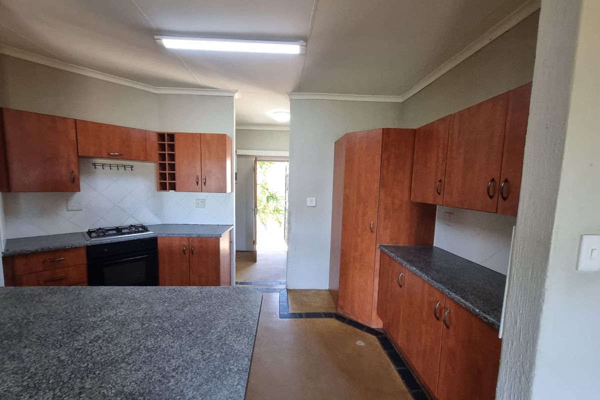 A functional kitchen featuring wooden cabinetry, granite countertops, and a built-in gas hob and oven, offering a practical layout for daily meal preparation.