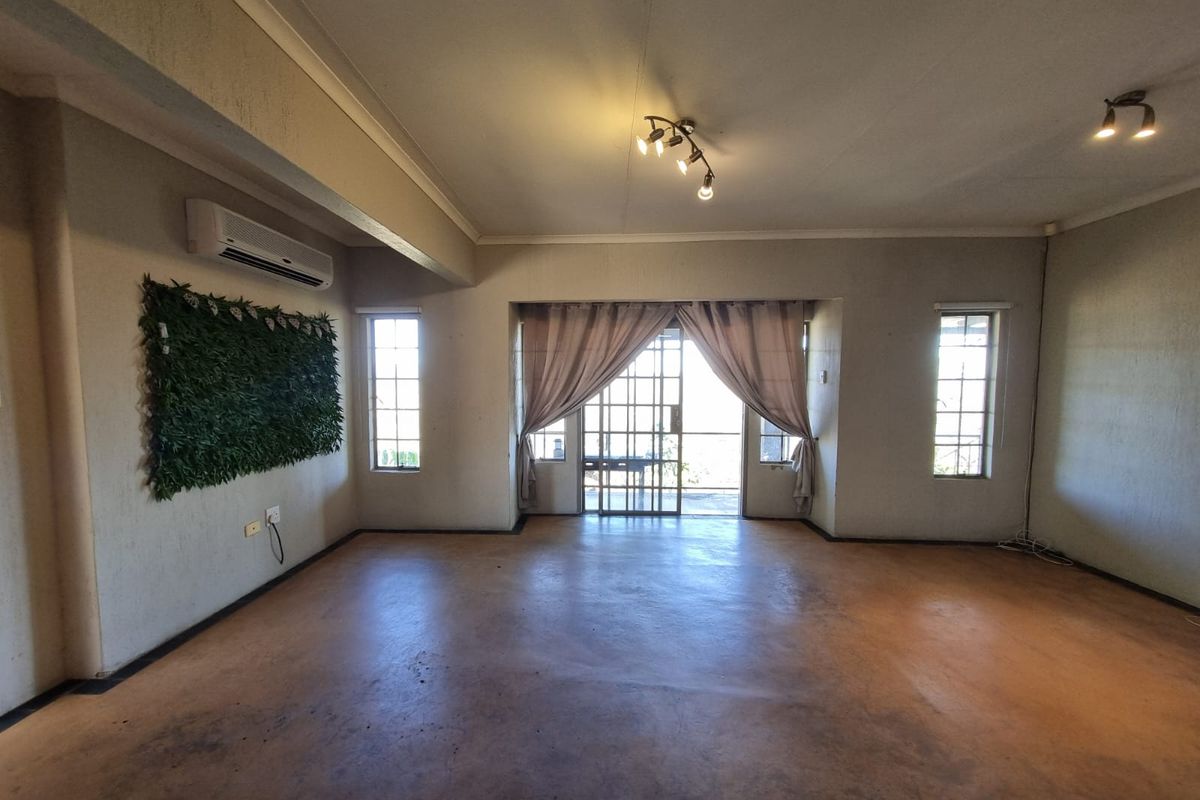 Spacious living area featuring concrete flooring, air conditioning, and large sliding glass doors leading to an outdoor space.