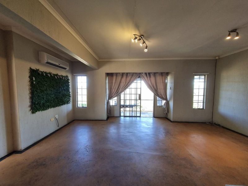 Spacious living area featuring concrete flooring, air conditioning, and large sliding glass doors leading to an outdoor space.