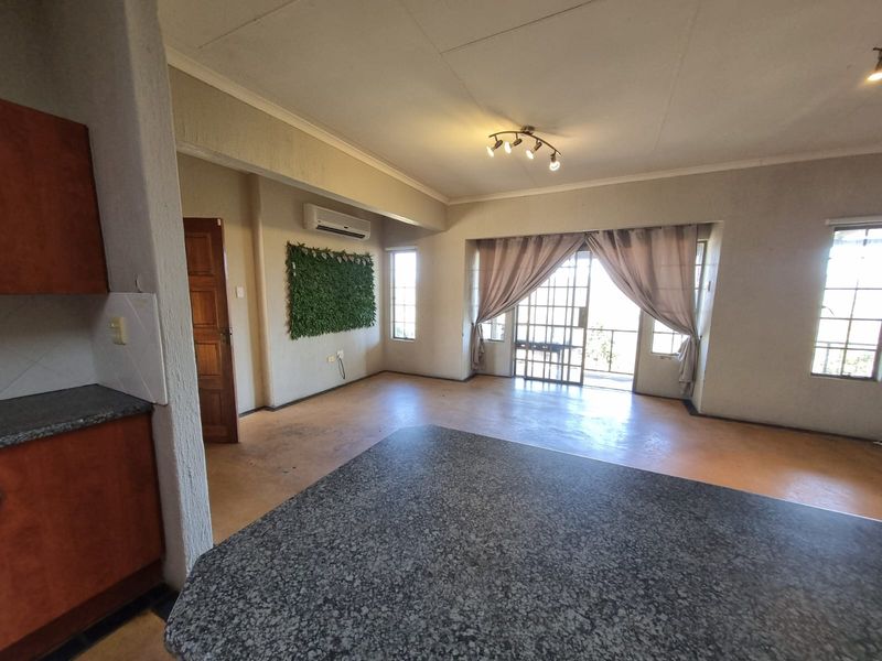 Spacious open-plan living area featuring a granite kitchen island, split-system air conditioning, and direct access to an outdoor patio through sliding glass doors.
