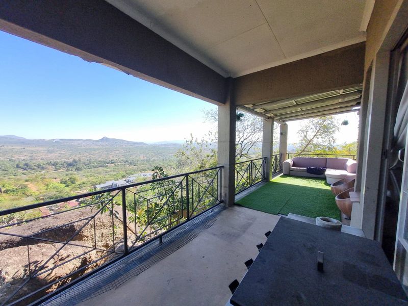 A spacious covered balcony featuring a metal balustrade and panoramic views of the surrounding landscape.