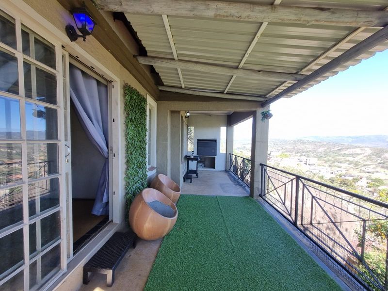 Covered balcony featuring a built-in braai, metal railing, and expansive views, providing an ideal space for outdoor entertaining.