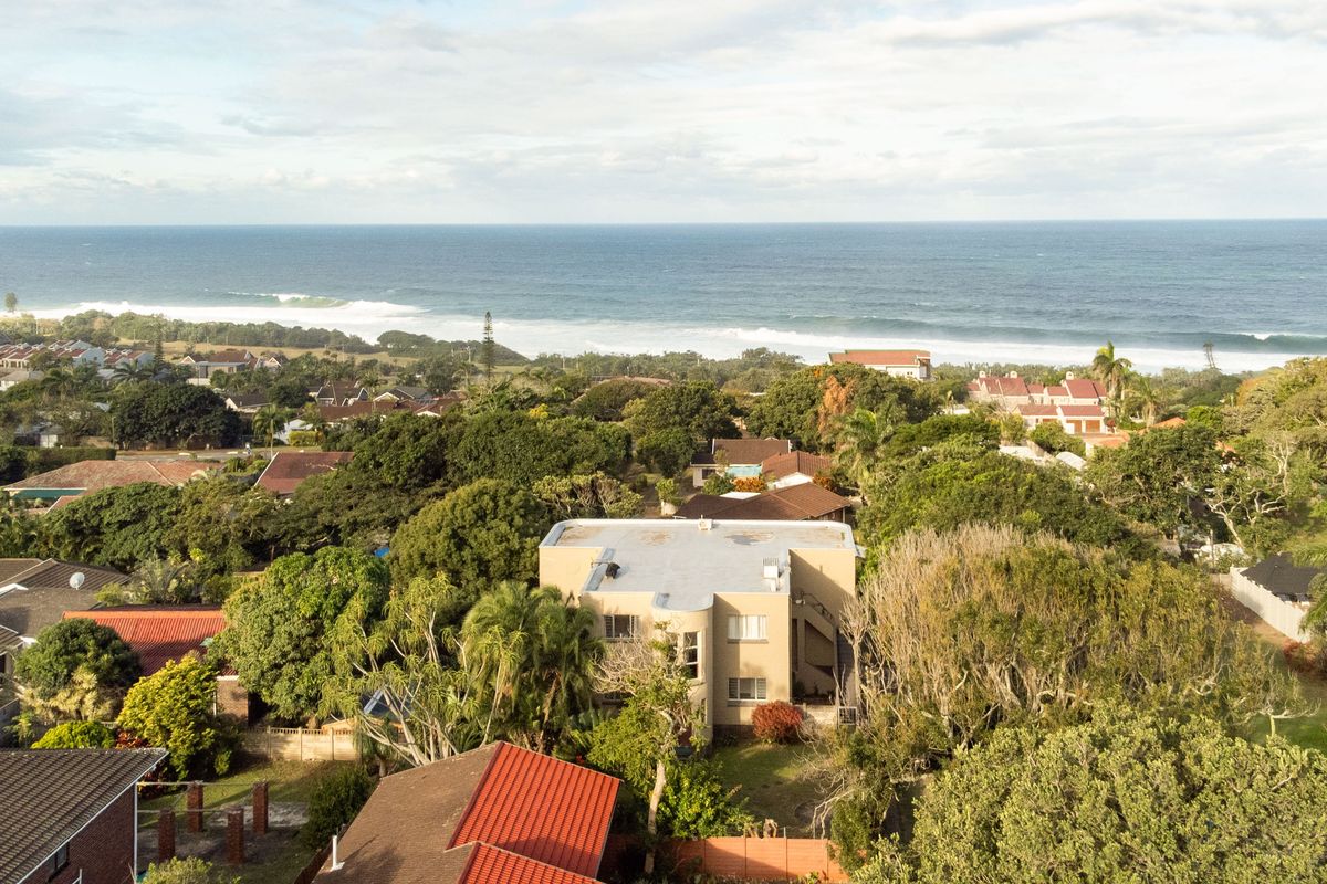 An aerial view of the townhouse property, showcasing its location within a lush, green coastal neighborhood with proximity to the ocean.