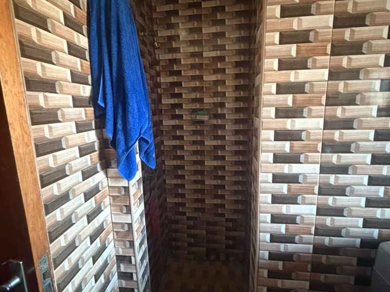 A compact shower enclosure featuring full-height decorative textured wall tiling and matching floor tiles.