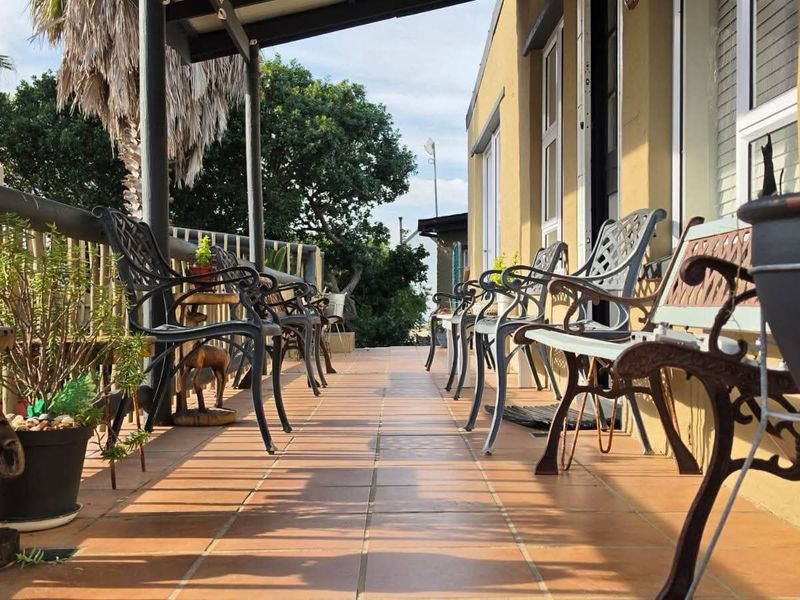 A covered outdoor patio featuring tiled flooring and a metal railing, providing a functional space for outdoor relaxation.