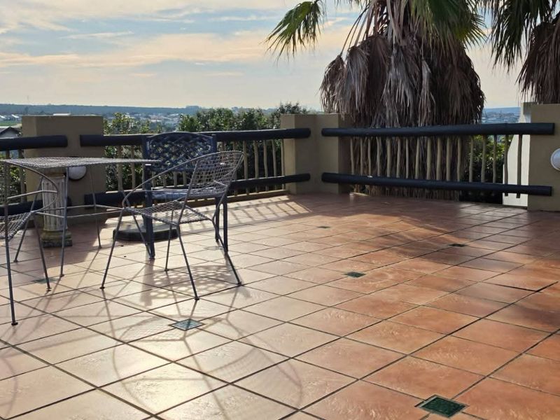 Spacious outdoor patio featuring tiled flooring and timber railings, offering an elevated view of the surrounding area.