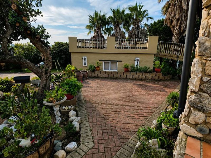 A well-maintained rear courtyard featuring brick paving, stone-clad exterior walls, and a raised terrace area with metal railings.
