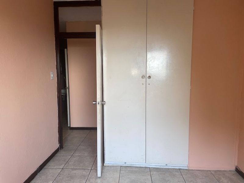An empty bedroom featuring tiled flooring and a built-in wardrobe, offering a blank canvas for potential updates and interior design.