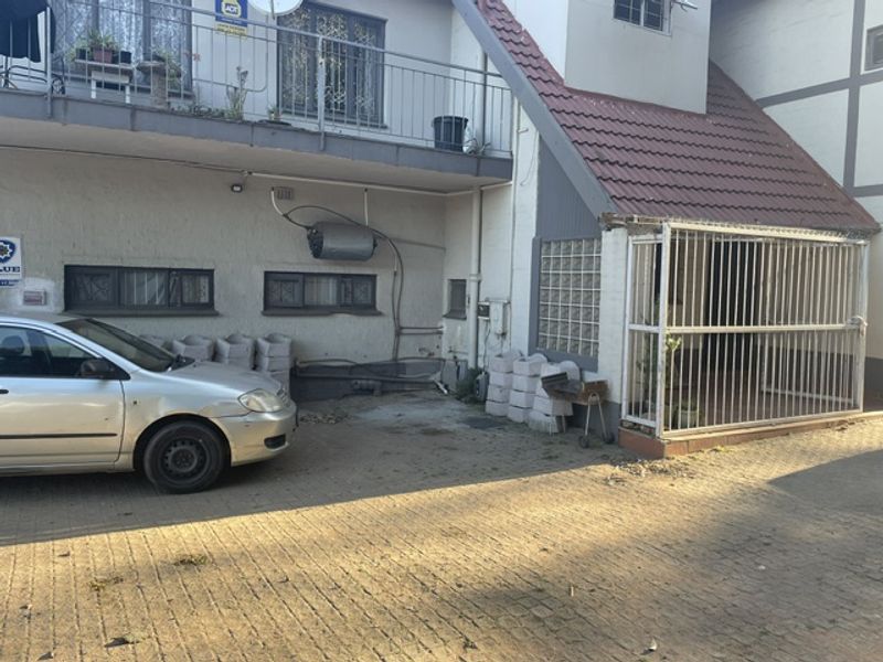 Front exterior view of the property featuring a paved driveway, security gate, and balcony with metal railings.