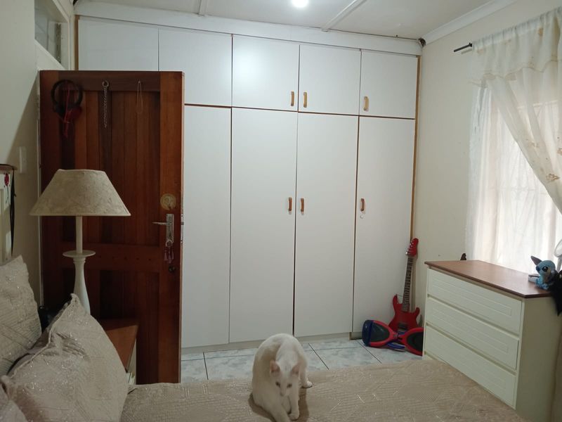 A bedroom featuring white built-in cupboards, tiled flooring, and a solid timber door.