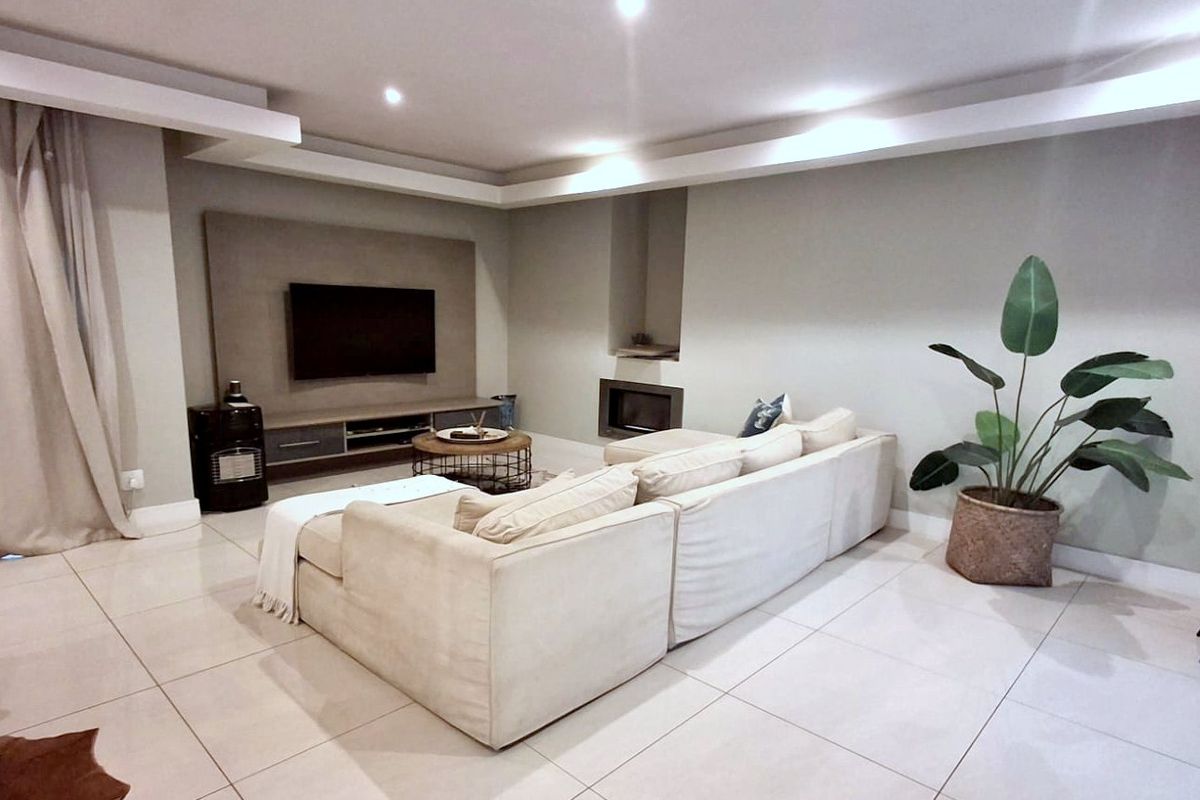 Spacious living room featuring modern tiled flooring, a bulkhead ceiling with recessed lighting, and a built-in fireplace.