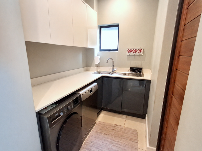 A compact and functional scullery featuring modern built-in cabinetry, a stainless steel sink with mixer tap, and space for under-counter appliances.