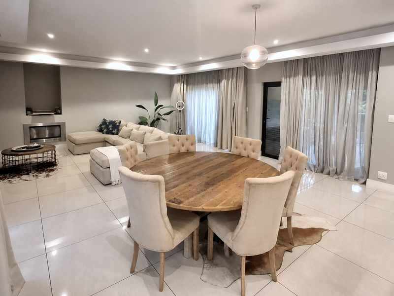 Spacious open-plan living and dining area featuring polished porcelain tiles, recessed ceiling lighting, a modern built-in fireplace, and large sliding doors to the patio.