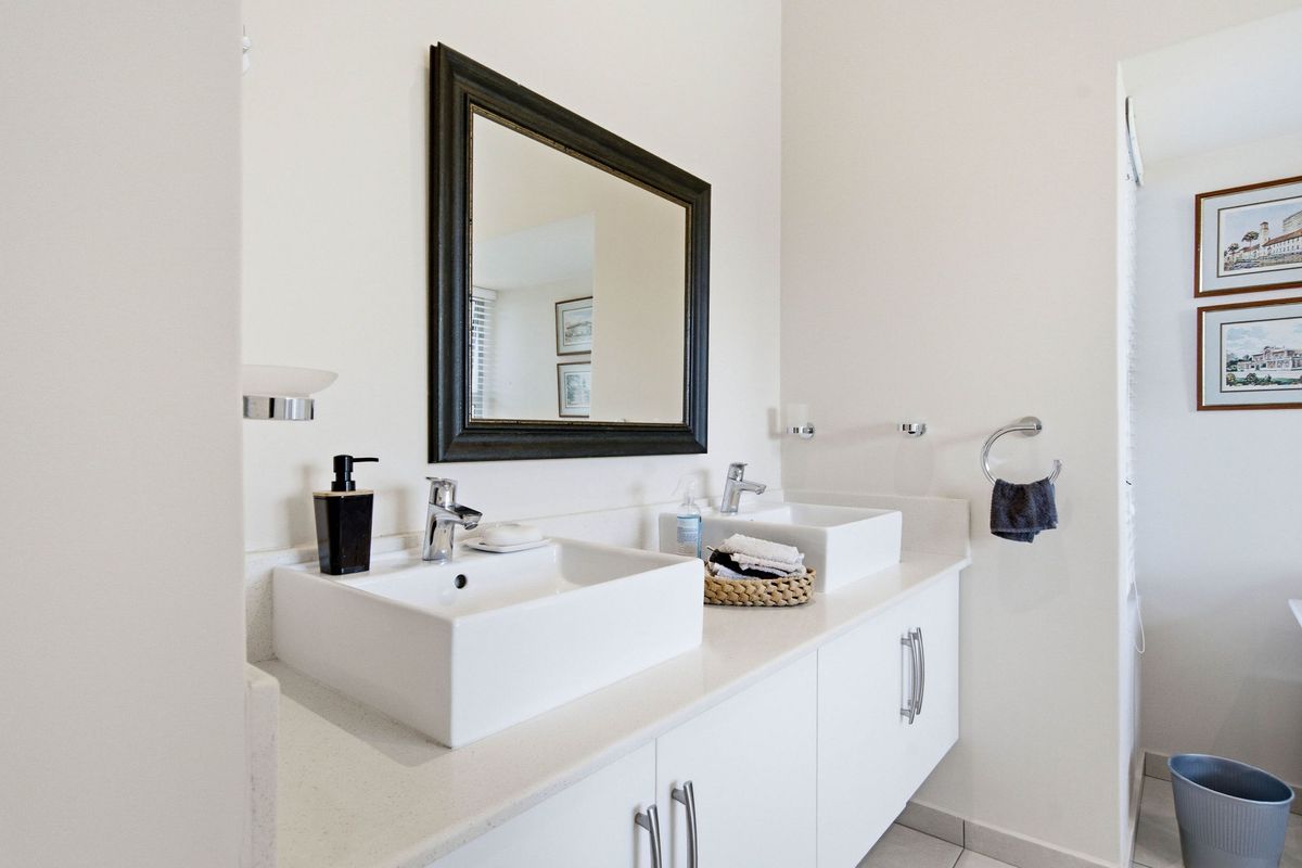 Modern bathroom featuring a double vanity with white vessel sinks, chrome fixtures, stone countertop, and ample built-in storage cabinetry.