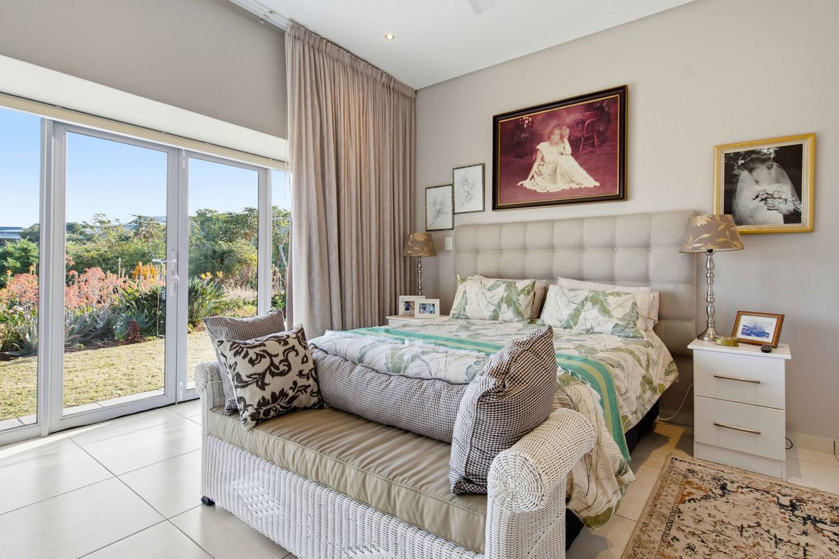 A bright bedroom featuring tiled flooring, recessed lighting, and a large sliding glass door providing direct access to the garden.