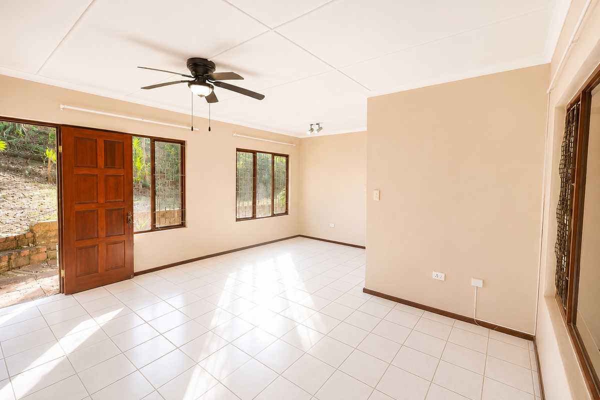 A bright, empty living room featuring tiled floors, a ceiling fan, and direct access to the outdoor area through a timber door.