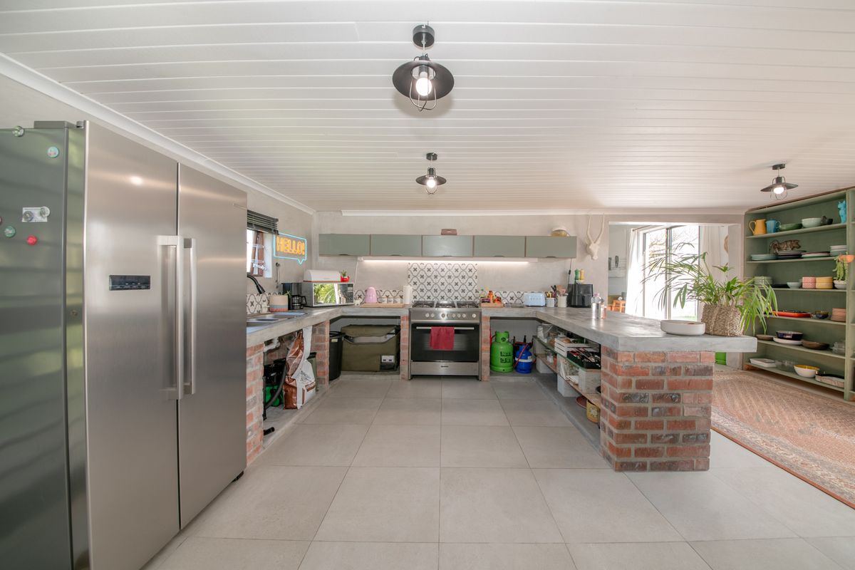 Spacious kitchen featuring unique exposed brick cabinetry bases, concrete countertops, gas stove, and tiled flooring with a modern farmhouse aesthetic.