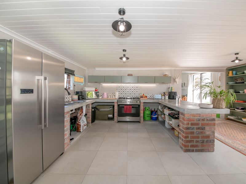 Spacious kitchen featuring unique exposed brick cabinetry bases, concrete countertops, gas stove, and tiled flooring with a modern farmhouse aesthetic.