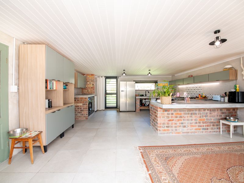 Spacious open-plan kitchen featuring exposed brick elements, concrete countertops, modern cabinetry, and tiled flooring, creating a rustic yet contemporary living space.
