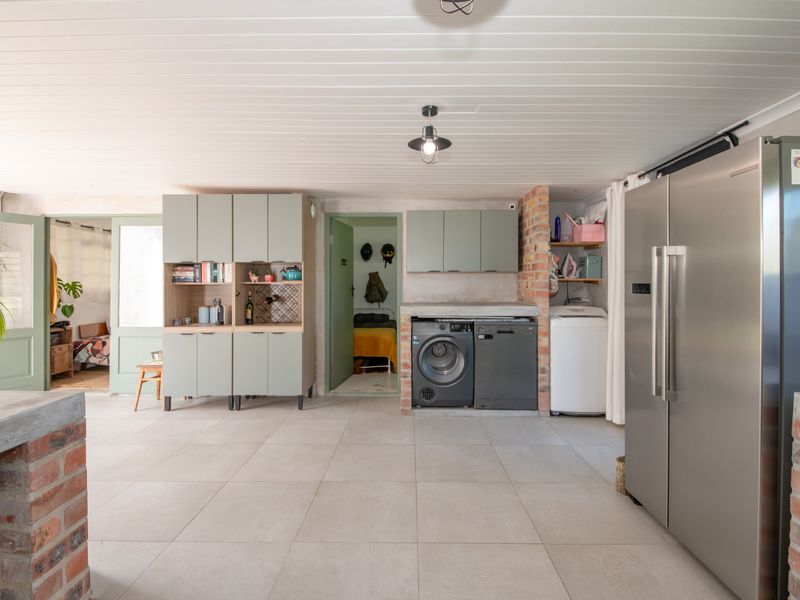 A functional laundry area featuring exposed brick accents, modern cabinetry, tiled flooring, and integrated space for laundry appliances.