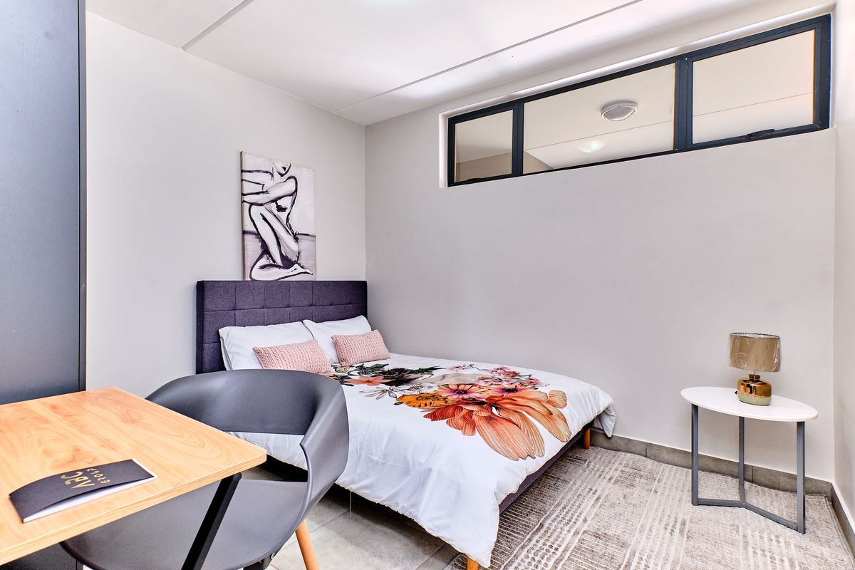 A well-maintained bedroom featuring neutral walls, tiled flooring, and a high-level clerestory window providing natural light.