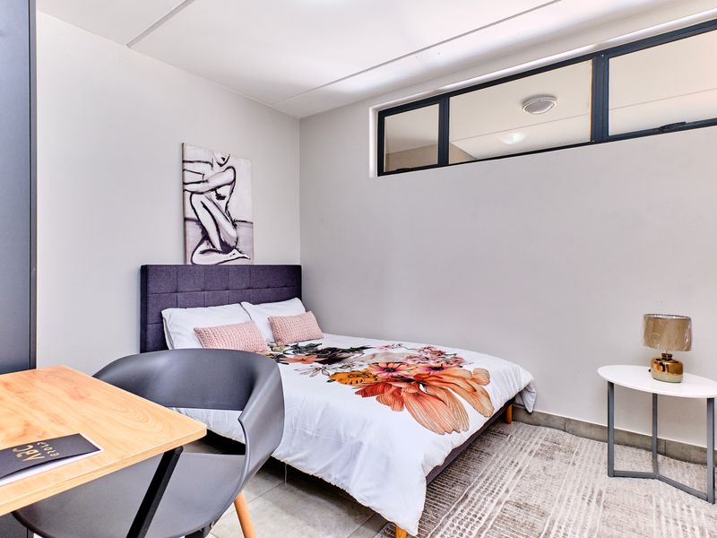 A well-maintained bedroom featuring neutral walls, tiled flooring, and a high-level clerestory window providing natural light.