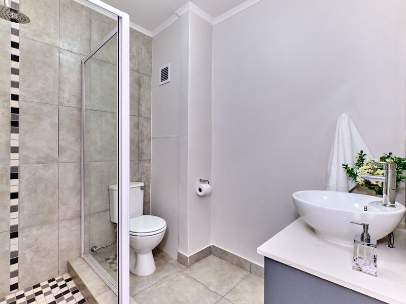 Modern bathroom featuring a glass-enclosed shower, a contemporary basin vanity, and neutral floor-to-ceiling tiling.