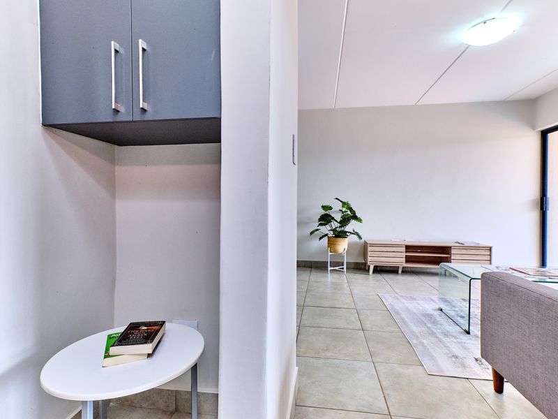 A bright living area featuring neutral tiled flooring and built-in overhead storage cabinetry, offering a clean and functional space.