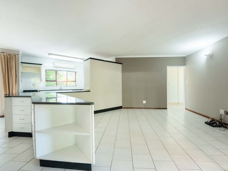Spacious open-plan living and kitchen area featuring tiled flooring, a central kitchen island with granite countertops, and direct access to the outdoor patio.