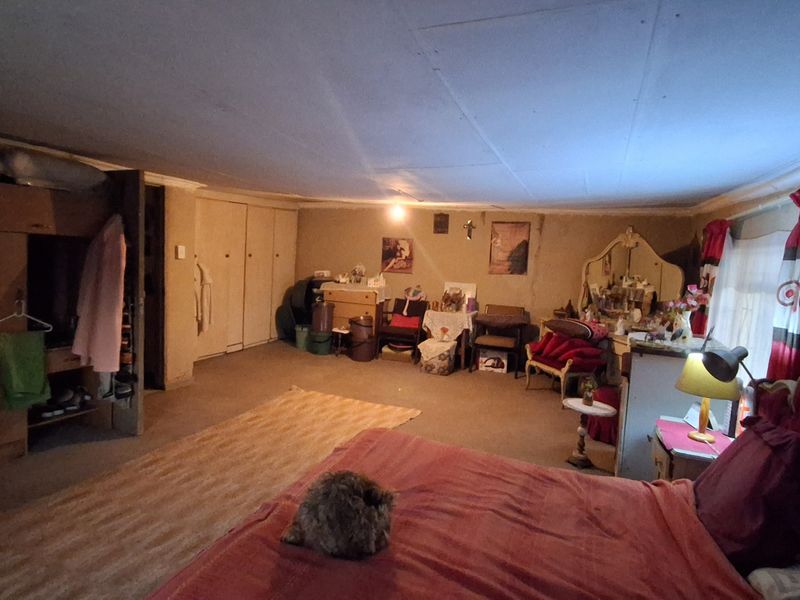 Spacious bedroom featuring built-in cupboards, carpeted flooring, and coved ceiling details, offering a generous layout ready for modernization and cosmetic updates.