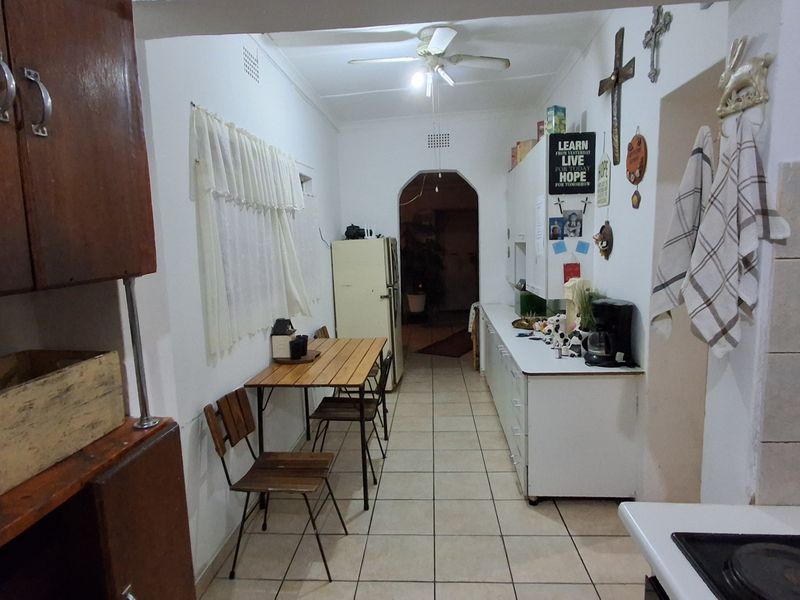 A functional kitchen featuring tiled flooring, built-in cabinetry, and a ceiling fan, offering a dated aesthetic with potential for modernization.