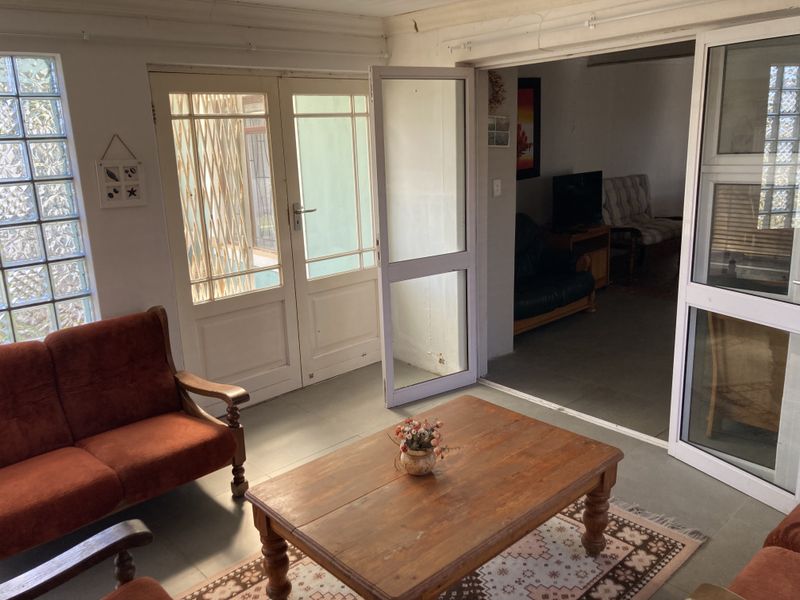 A living area featuring glass block windows, tiled flooring, and double doors leading to an adjacent room.
