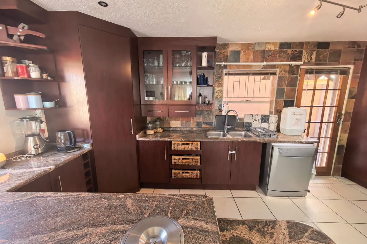 A functional kitchen featuring dark wood cabinetry, granite countertops, slate tile backsplash, and tiled flooring, offering a classic aesthetic with potential for modern updates.