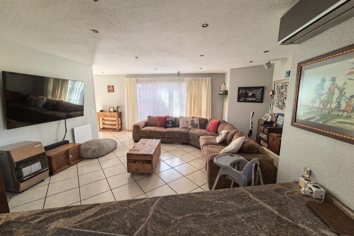 Spacious living room featuring tiled flooring, recessed lighting, and a split-system air conditioner, with direct access to the outdoor area through sliding glass doors.