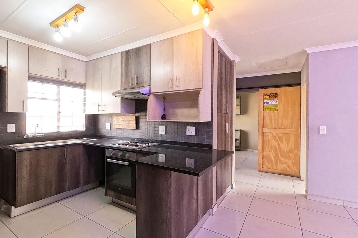 Modern kitchen featuring dark wood-look cabinetry, granite countertops, built-in oven, gas hob, and tiled flooring in an open-plan layout.