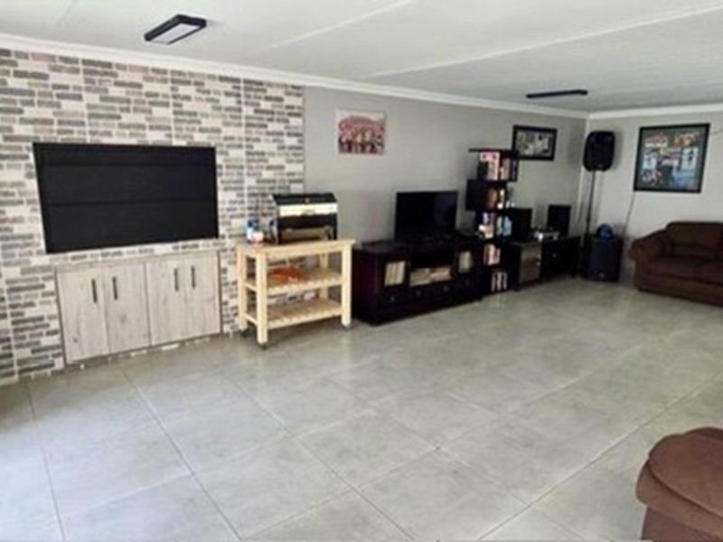 Spacious living room featuring a brick-cladding accent wall, neutral tiled flooring, and large sliding glass doors providing ample natural light.